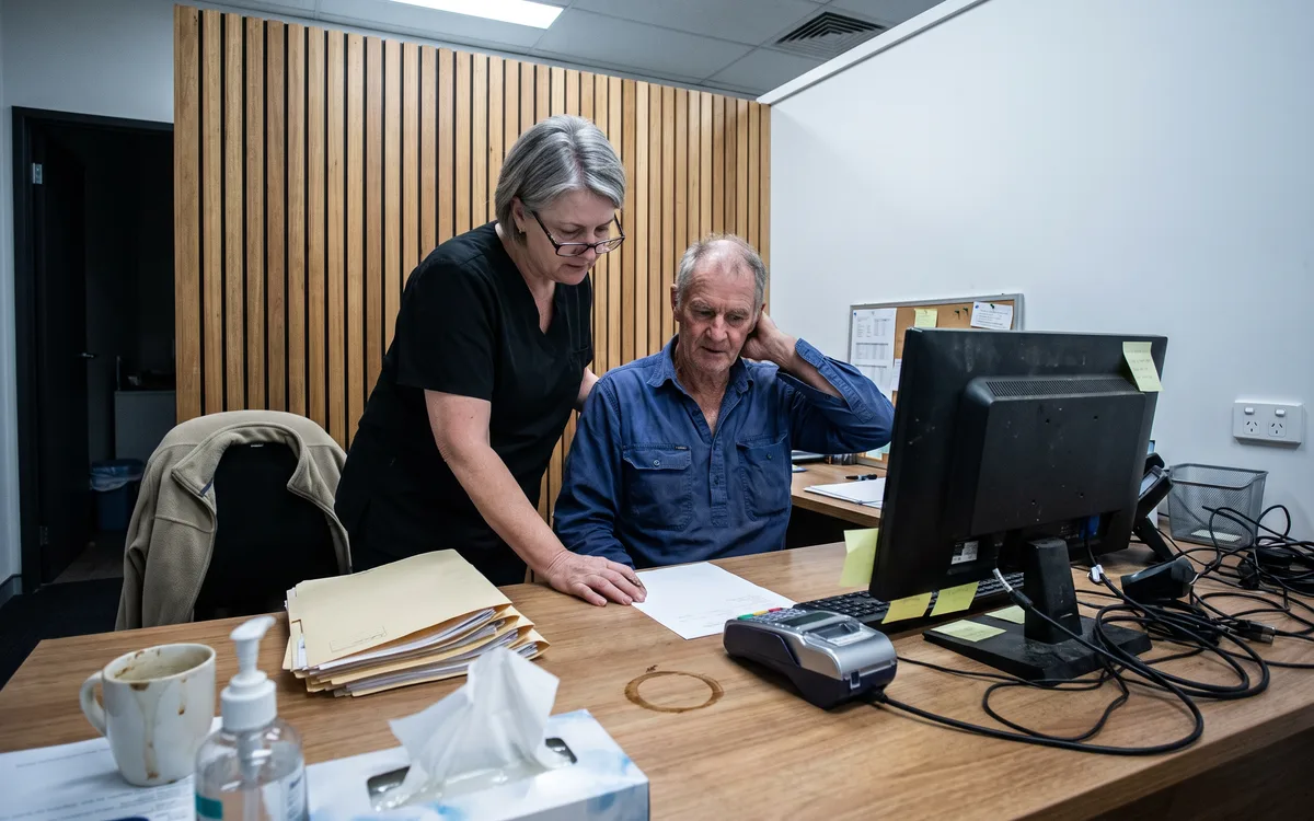 A treatment coordinator sitting beside a patient at Enhanced Dental Studios, going through a printed treatment plan together.